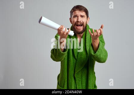 uomo emozionale in un vestito verde con un foglio laminato di carta su uno sfondo chiaro vista ritagliata Foto Stock