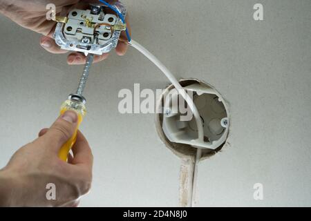 L'elettricista collega le prese ai fili elettrici. Cavo di installazione in una spina. Un uomo installa una presa elettrica a muro. Primo piano di Foto Stock