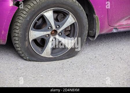 primo piano pneumatico sgonfio per auto civile in giornata di sole a secco superficie in asfalto grigio Foto Stock