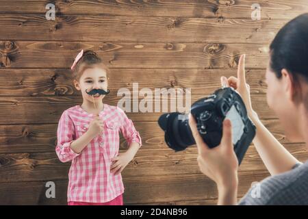 Fotografo in movimento. Giovane fotografo donna e bambina che si diverte alla sessione fotografica. Foto Stock