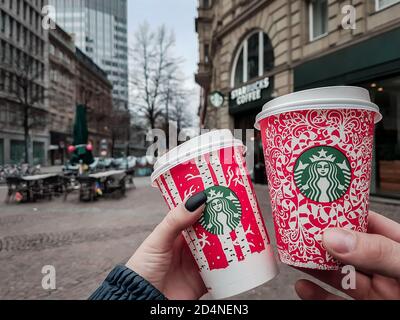 Colonia / Germania - Capodanno 2018: Due persone che tengono le tazze rosse di Natale di Starbucks davanti al caffè di Colonia. Tazza monouso in edizione speciale Foto Stock