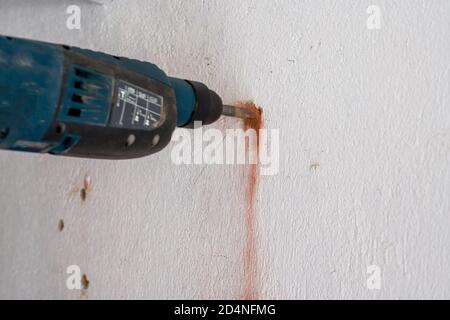 Un lavoratore sta perforando un buco nella parete con un trapano a percussione Foto Stock