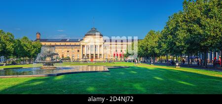 Wiesbaden, Germania, 24 agosto 2019: Panorama di Kurhaus o curativo casa termale e casinò edificio e Bowling Green parco con prato erboso, vicolo alberi e stagno con fontana nel centro storico della città Foto Stock