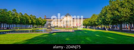 Wiesbaden, Germania, 24 agosto 2019: Panorama di Kurhaus o curativo casa termale e casinò edificio e Bowling Green parco con prato erboso, vicolo alberi e stagno con fontana nel centro storico della città Foto Stock