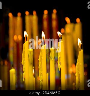 Una vista ravvicinata delle candele gialle brucianti del tempio Un wat buddista in Asia Foto Stock