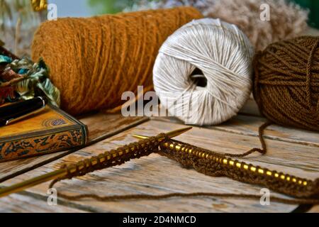 Concetto di relax con accessori assortiti per maglieria in una composizione di natura morta con caldi colori rustici. Foto Stock