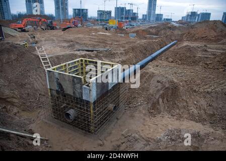 Collegamento di uno scarico a trincea a una struttura di tombino in cemento in cantiere. Pila di calcestruzzo in cassaforma per costruire acque piovane e sottogru Foto Stock