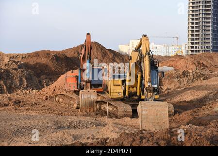 Gruppo di escavatori per scavare trincee in un cantiere per fondare e installare tubi per tempeste. Scavo del retroescavatore per fossato della tubazione. Foto Stock