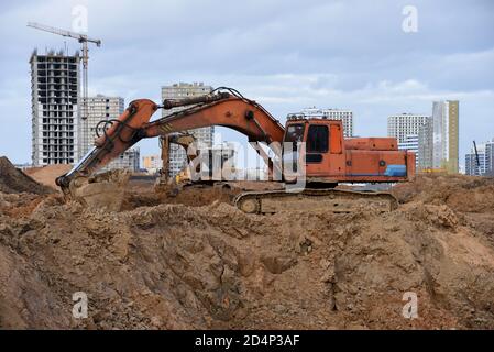 Gruppo di escavatori per scavare trincee in un cantiere per fondare e installare tubi per tempeste. Scavo del retroescavatore per fossato della tubazione. Foto Stock