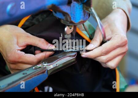 sarto, seamstress. Ago della macchina da cucire in movimento. Il processo di cucitura della corda nel tessuto in una macchina da cucire da vicino. Il dispositivo personalizzato chiama il Foto Stock