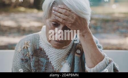 Ritratto di una donna anziana preoccupata che tiene la mano sulla fronte nel parco. Foto di alta qualità Foto Stock