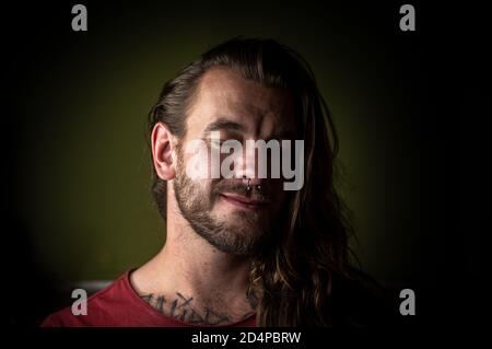 Il giovane uomo dai capelli lunghi indulge in un sogno di giorno con il suo occhi chiusi Foto Stock