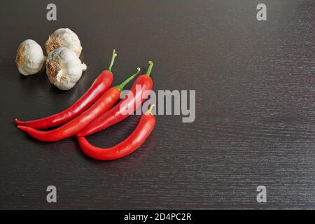 Peperoncino rosso e aglio crudo su tavolo nero testurizzato Foto Stock