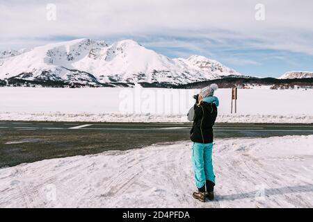 La fotografa donna fotografa una montagna innevata in inverno. Foto Stock