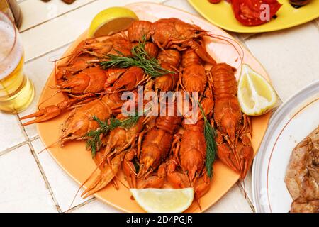 Gamberi bolliti rossi con fette di limone sul tavolo. Messa a fuoco superficiale. Foto Stock