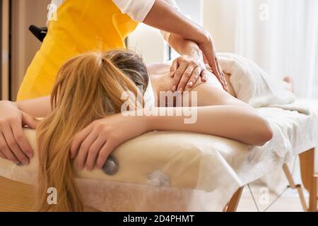 Giovane donna che riceve un massaggio alla schiena in un centro medico. La paziente femminile sta ricevendo un trattamento da un terapeuta professionista con le mani belle. Corpo Foto Stock