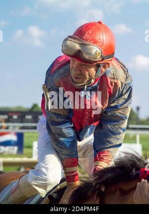 Jockey seduto coperto di fango dopo gara di cavalli Foto Stock