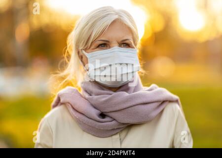 Ritratto di donna anziana che indossa una maschera protettiva per il viso all'aperto Foto Stock