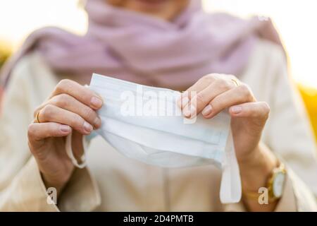 Primo piano delle mani di Senior Woman con maschera protettiva per il viso Foto Stock