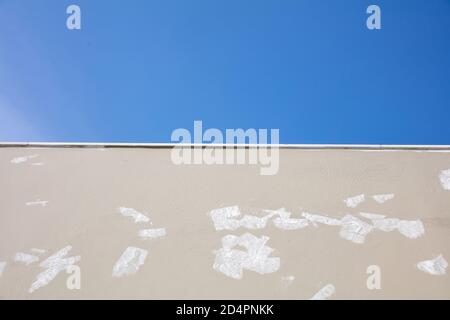 Preparazione della verniciatura della facciata dell'edificio. Parete esterna di colore beige preparata per la colorazione su sfondo blu chiaro del cielo. Spazio di copia, angolo basso frontale v Foto Stock