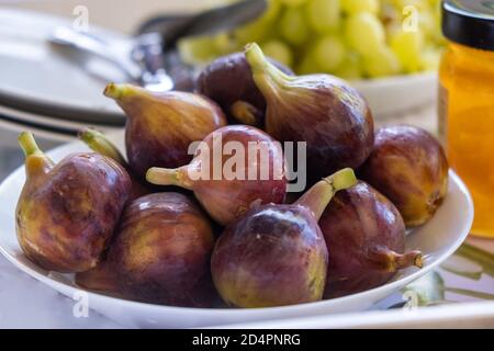 Fichi interi purpuri freschi, ficus carica e conservi di questi frutti dolci con vitamine e calorie. Cibo di nutrizione adeguato per vegan, vegetariano, Foto Stock