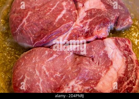 Concetto di carne. I lonini di maiale crudi si traccano in padella con olio pronto per essere fritto. Bistecche non cotte su fette di sfondo, guardaroba, vista dall'alto. Foto Stock