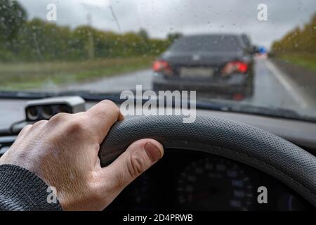 mano del conducente sul volante di una vettura in si è verificato un ingorgo a causa di interventi di riparazione su strada Foto Stock