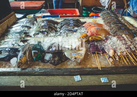 Vendita di prodotti ittici in un chiosco di strada in Thailandia. Diversi tipi di pesce esposti per la vendita. Foto Stock