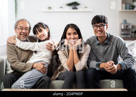 Ritratto di gruppo della famiglia asiatica felice multigenerazionale sedersi sul divano in soggiorno con sorriso. Muti genration famiglia felicità concetto. Foto Stock