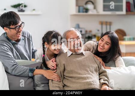 Ritratto di gruppo della famiglia asiatica felice multigenerazionale sedersi sul divano in soggiorno con sorriso. Muti genration famiglia felicità concetto. Foto Stock