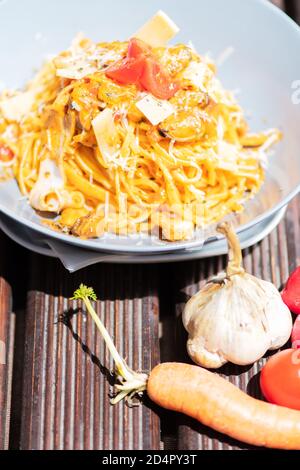 Gustosa e appetitosa pasta italiana di spaghetti con salsa, parmigiano e basilico sul piatto. Foto Stock