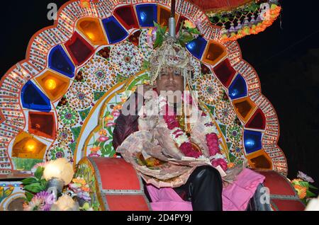 Sposo indiano intelligente seduto su un Baggi di nozze con luci colorate durante la processione del matrimonio che va verso il posto della sposa ad Agra, India Foto Stock