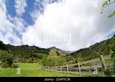 Immagine panoramica del sentiero con rotaia di legno sul lato destro e Alpi sullo sfondo che conduce alla cascata vicino a Partschins, Tirolo Sud, Ital Foto Stock