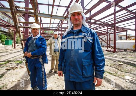 Shymkent/Kazakhstan - Aprile 27 2012: Costruzione di un nuovo edificio industriale. Lavoratori che posano sullo sfondo della struttura metallica dell'edificio. Foto Stock