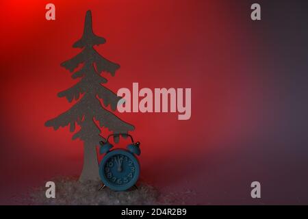 Albero di Natale con una sveglia blu su un rosso sfondo e spazio di copia Foto Stock
