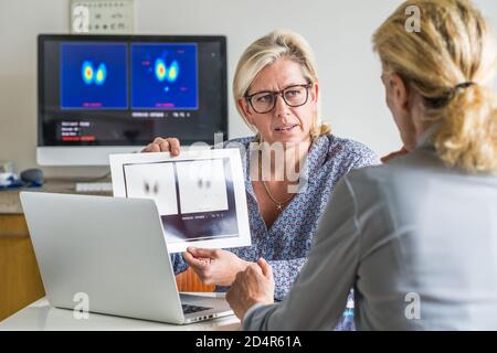 Medico a discutere di una ghiandola tiroidea scintigramma con un paziente femmina. Foto Stock