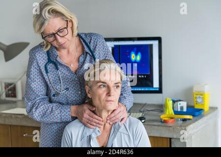 Medico di esaminare la ghiandola tiroide di un paziente. Foto Stock