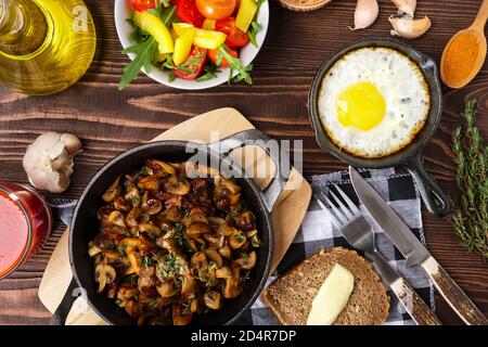 Funghi Fritti e l'uovo in cas-padella di ferro. Ingredienti per il rustico cibi semplici, vista dall'alto. Foto Stock