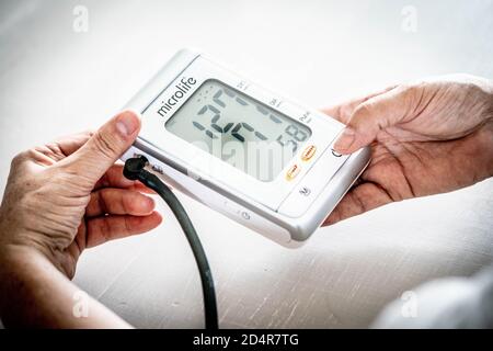 Donna prendendo la sua pressione del sangue con un portatile di monitor della pressione del sangue. Foto Stock