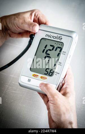 Donna prendendo la sua pressione del sangue con un portatile di monitor della pressione del sangue. Foto Stock