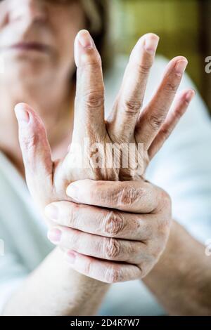 Senior donna che soffre di un dolore articolare in mano. Foto Stock