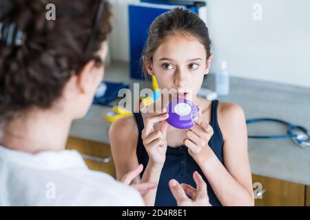 Medico di istruire una ragazza su come usare un inalatore per asmatici. Foto Stock