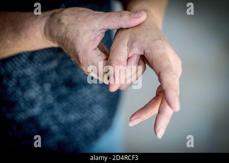 Senior donna che soffre di un dolore articolare in mano. Foto Stock