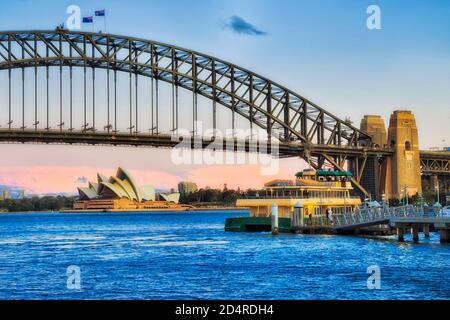 Sydney Ferry trasporto pubblico presso un molo sul porto di Sydney durante il tramonto con vista sul ponte del porto. Foto Stock