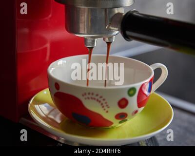 Preparazione del caffè con una macchina per il caffè. Primo piano di una macchina per il caffè. Primo piano di una colorata tazza per cappuccino. Preparazione di un cappuccino. Tazza per cappuccino Colorfup. Foto Stock