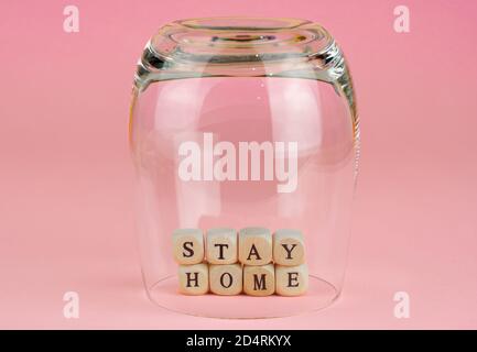 Le parole rimangono a casa sotto un bicchiere da bere su un rosa sfondo Foto Stock