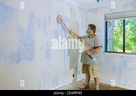 Il contraente che utilizza un cazzuola di sabbia levigando il muro a secco sulla parete Foto Stock