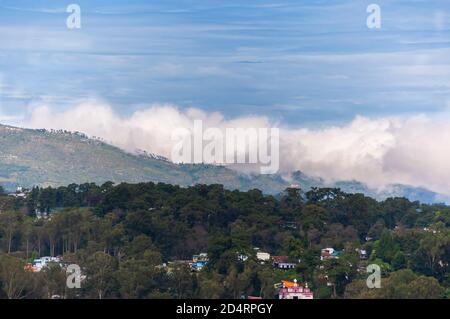 Fitte nuvole monsonone che si avvolgono sulla cresta di una montagna, in un giorno di ottobre parzialmente soleggiato a Shillong, Megalaya, India. Foto Stock