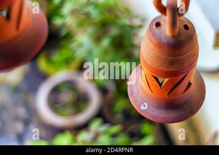 Un manufatto da giardino contenente una campana in argilla è sospeso nell'aria da una catena in ceramica/argilla/terracotta. Foto Stock
