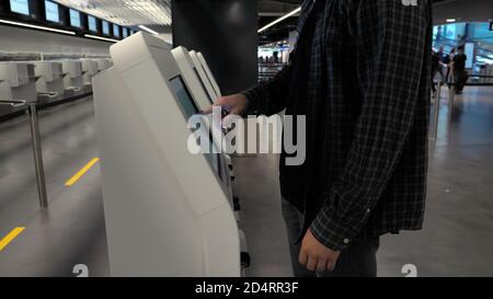 Uomo che usa la macchina del check-in all'aeroporto per ottenere la carta d'imbarco. Foto Stock